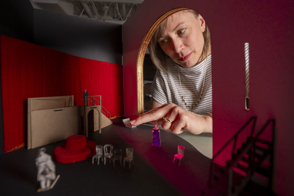 Sara Brown's hand reaches into a red-tinted stage model