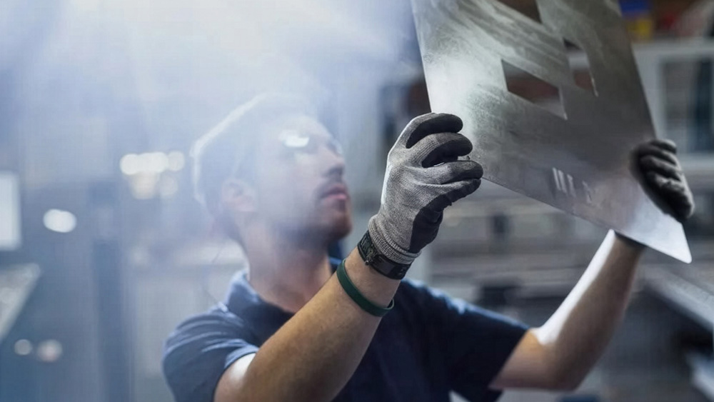 Worker holds and inspects a piece of metal