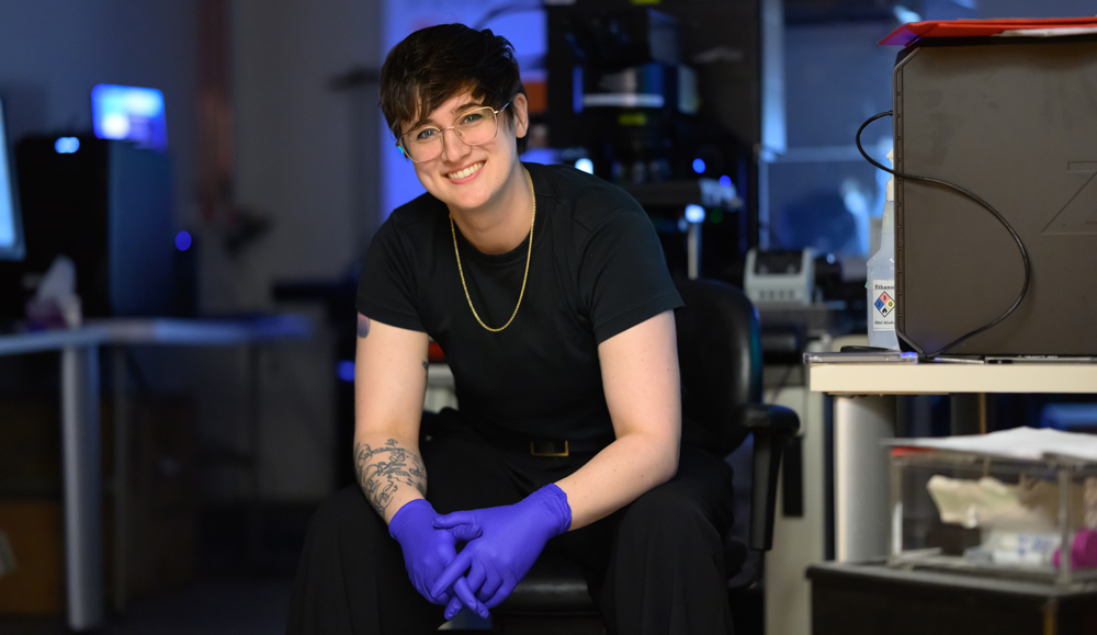 Shannon Knight portrait in lab, seated, wearing gloves
