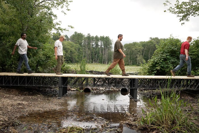 4 people cross a 3D-built bridge in wetlands