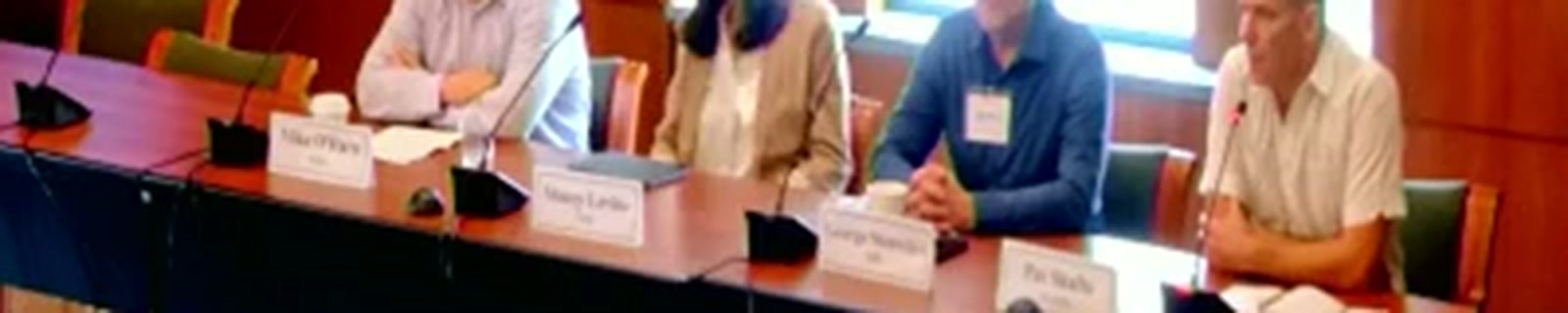 Table name cards, left to right: "Mike O'Hara," "Stacey Levine," "George Stantchev," "Pat Shafto," showing the panel's seating order